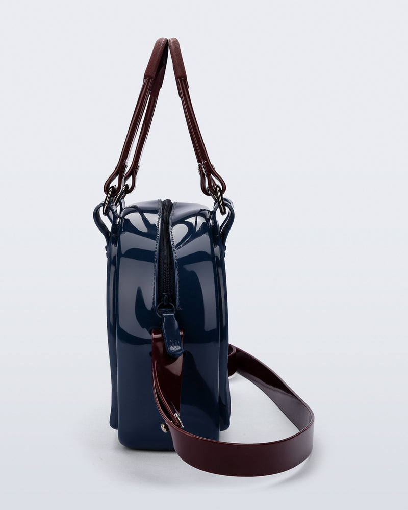 Side view of a blue Bowling bag with burgundy handle strap and cross body strap