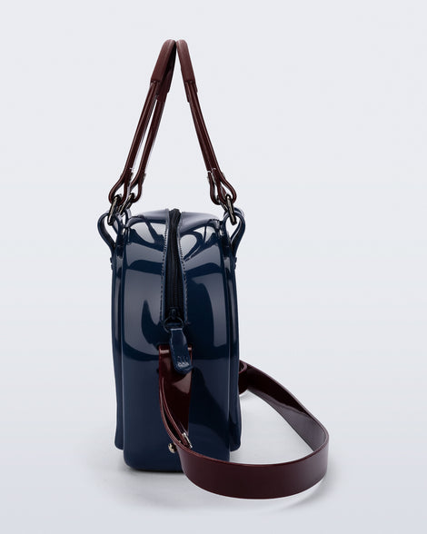 Side view of a blue Bowling bag with burgundy handle strap and cross body strap