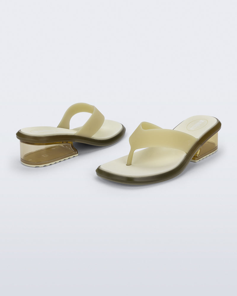 Back and angled view of a pair of beige Margot flip flops with clear beige low heel 
