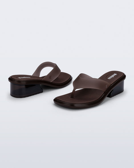Back and angled view of a pair of brown Margot flip flops with low heel 