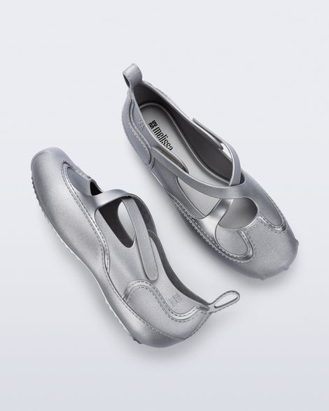 Top and side view of a pair of silver Aira flats with top straps