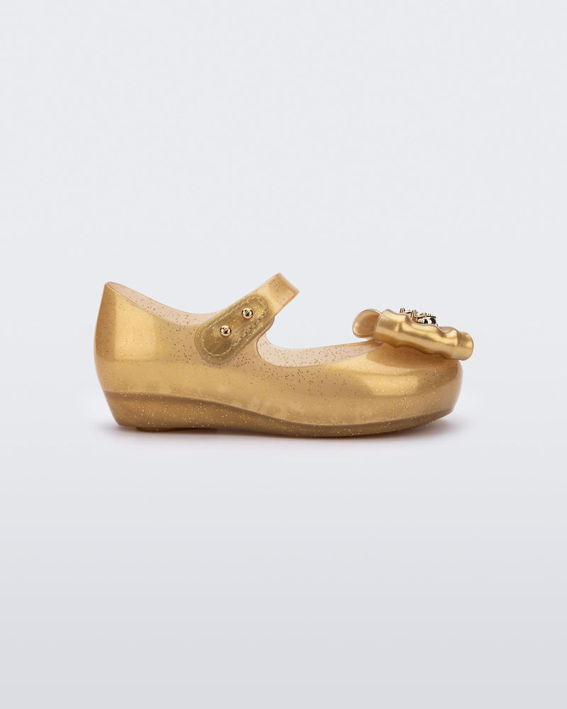 Side view of a glitter gold Ultragirl Princess ballerina baby flat with bow on top and silver details
