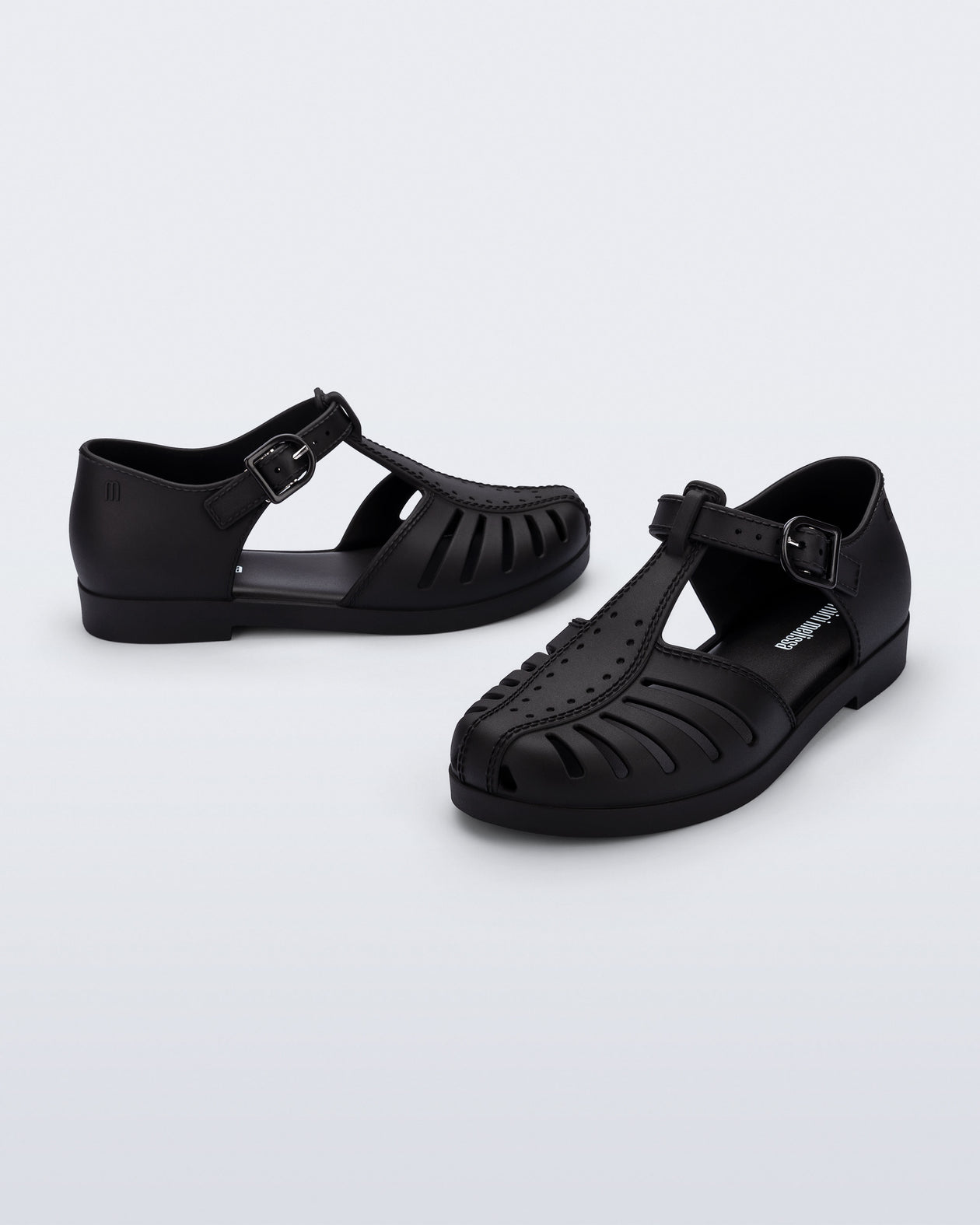 Side and angled view of a pair of black Aranha 79 kids flats with buckle