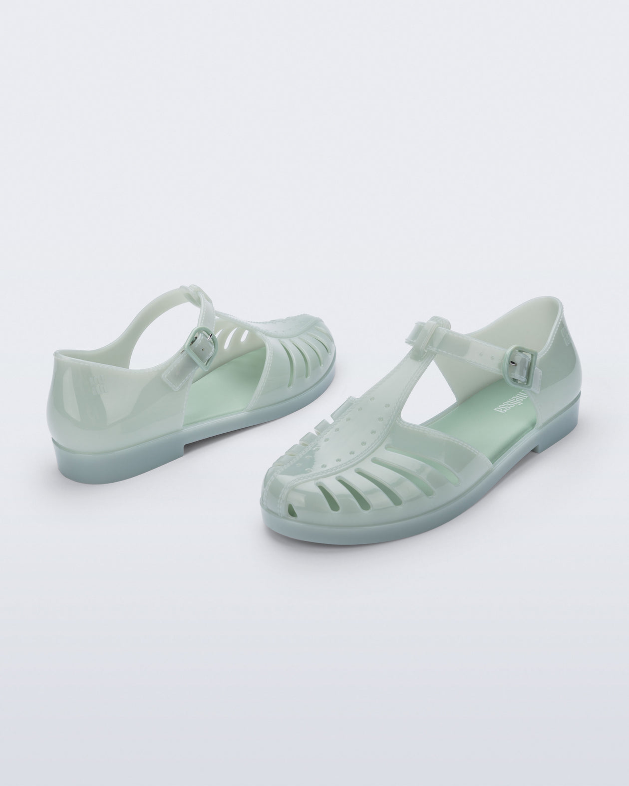 Back and angled view of a pair of milky green Aranha 79 flats with buckle