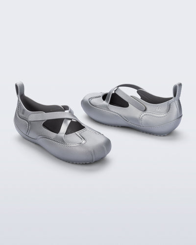 Back and angled view of a pair of silver Aira flats with top straps