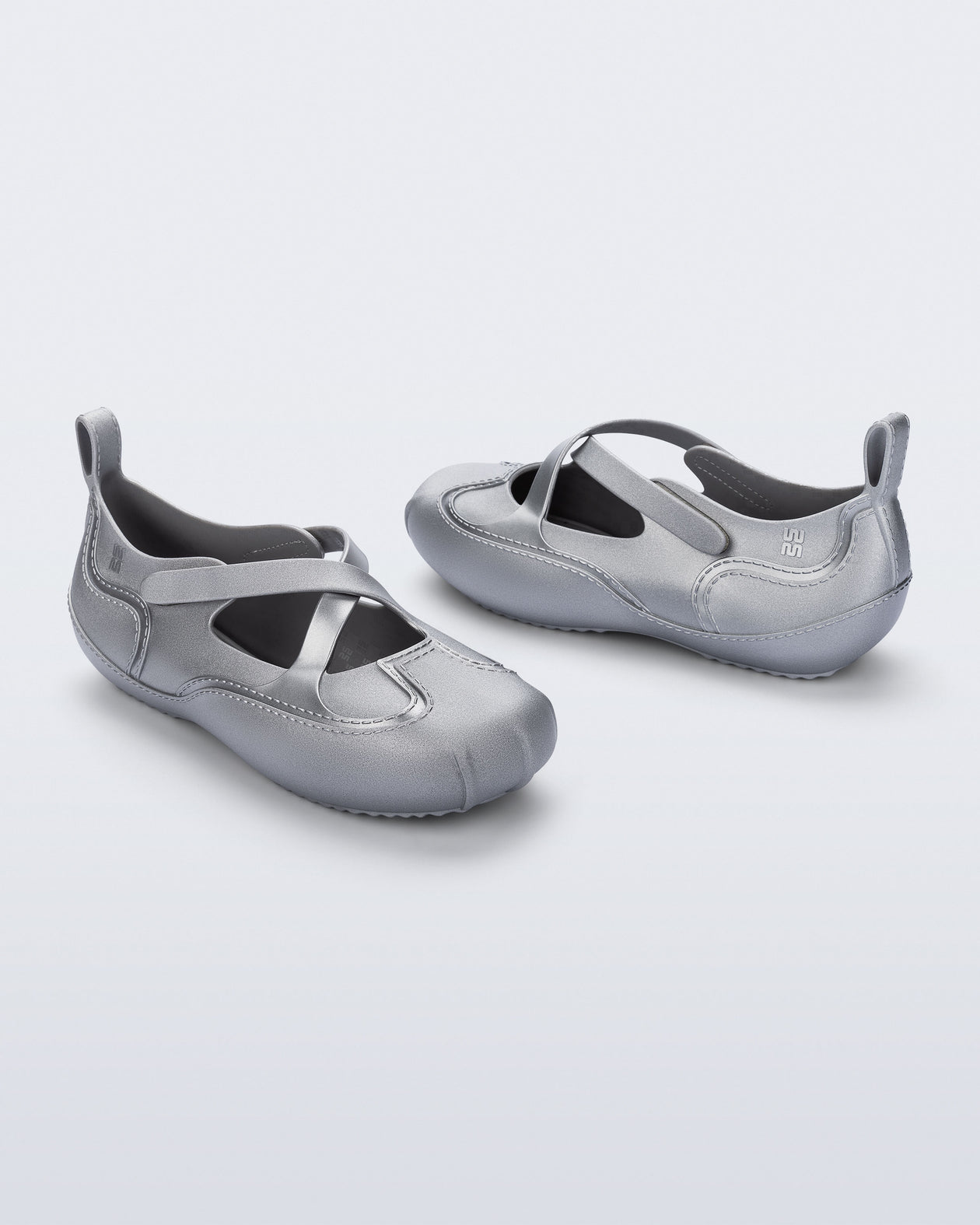 Back and angled view of a pair of silver Aira flats with top straps