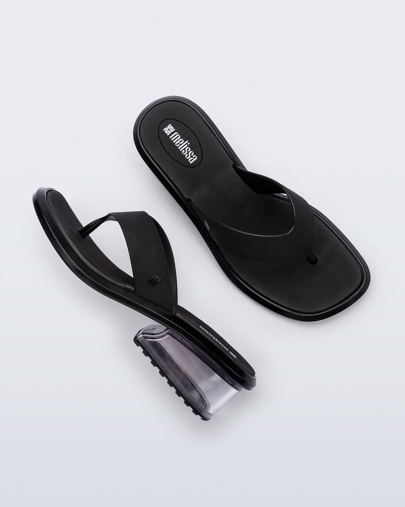Top and side view of a pair of black Margot flip flops with clear  low heel 