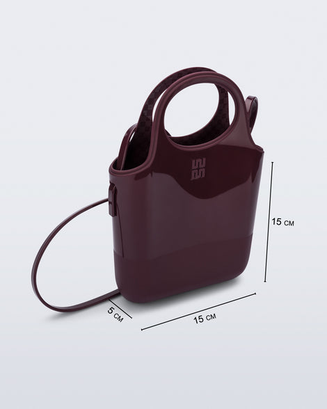 Angled view of a burgundy Ultra Bag with handle and strap with bag dimensions of 15cm x 5cm x 15cm