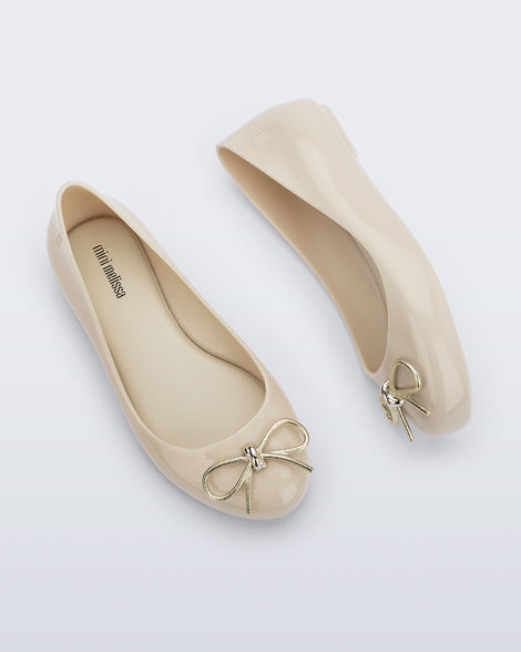 Side and top view of a pair of beige Sweet Love Chrome kids flats with metallic gold bow