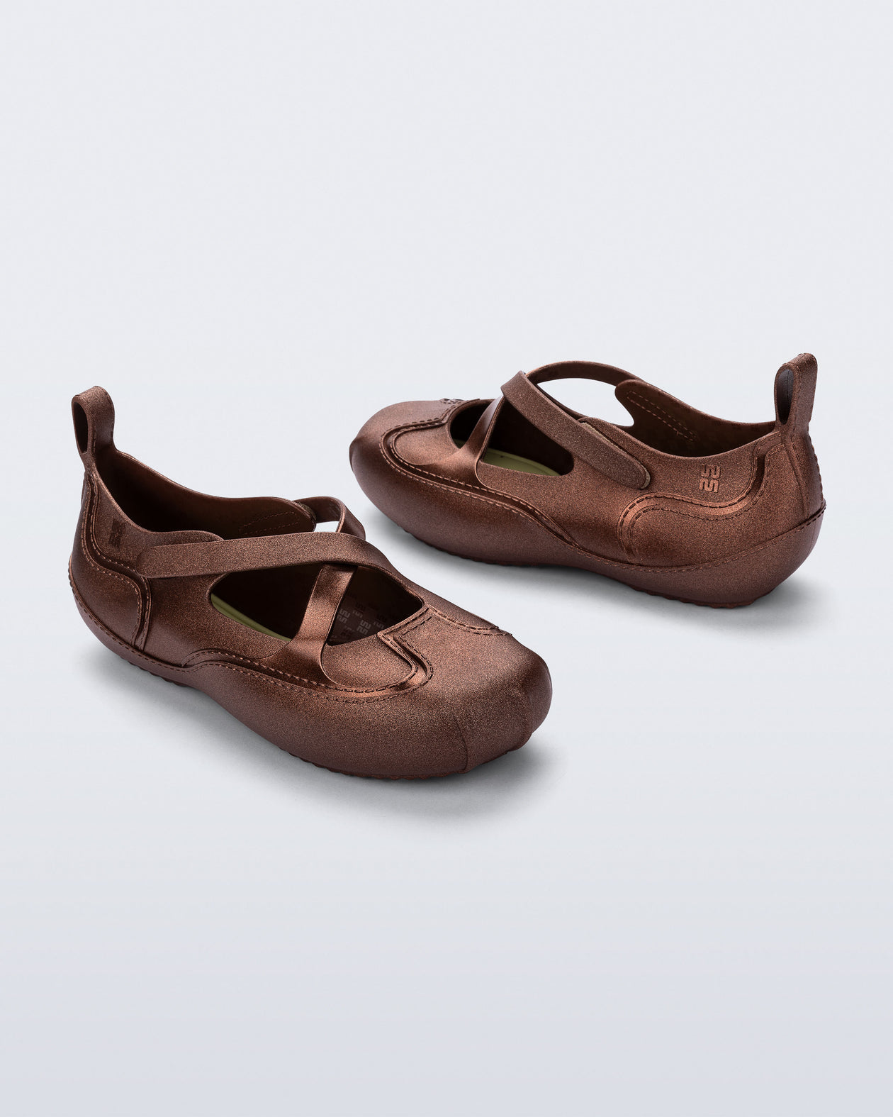 Back and angled view of a pair of bronze Aira flats with top straps