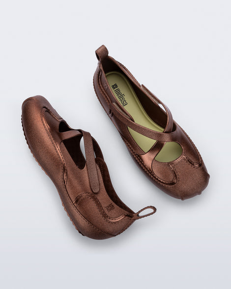 Top and side view of a pair of bronze Aira flats with top straps