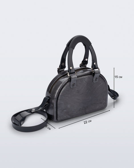 Angled view of a grey Bowling bag with black handle strap and cross body strap with bag dimensions of 22cm x 8cm x 15cm