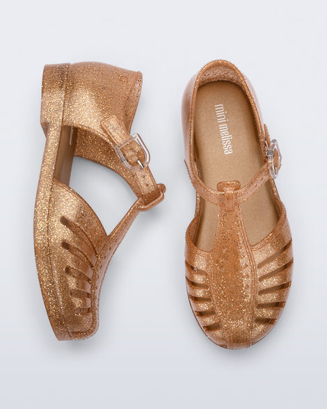 Side and top view of a pair of glitter gold Aranha 79 kids flats with buckle