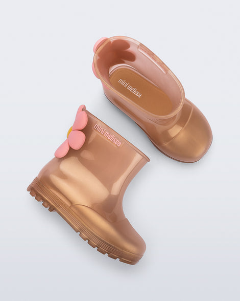 Side and top view of a pair of pearly pink Welly Bloomy boots with pink daisy on back