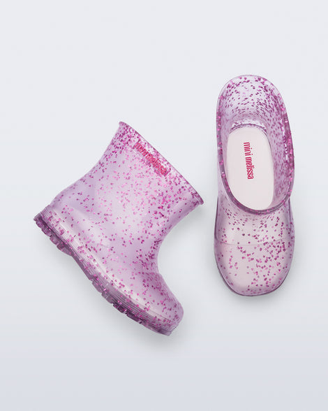 Top and side view of a pair of clear with pink glitter Welly baby rain boots