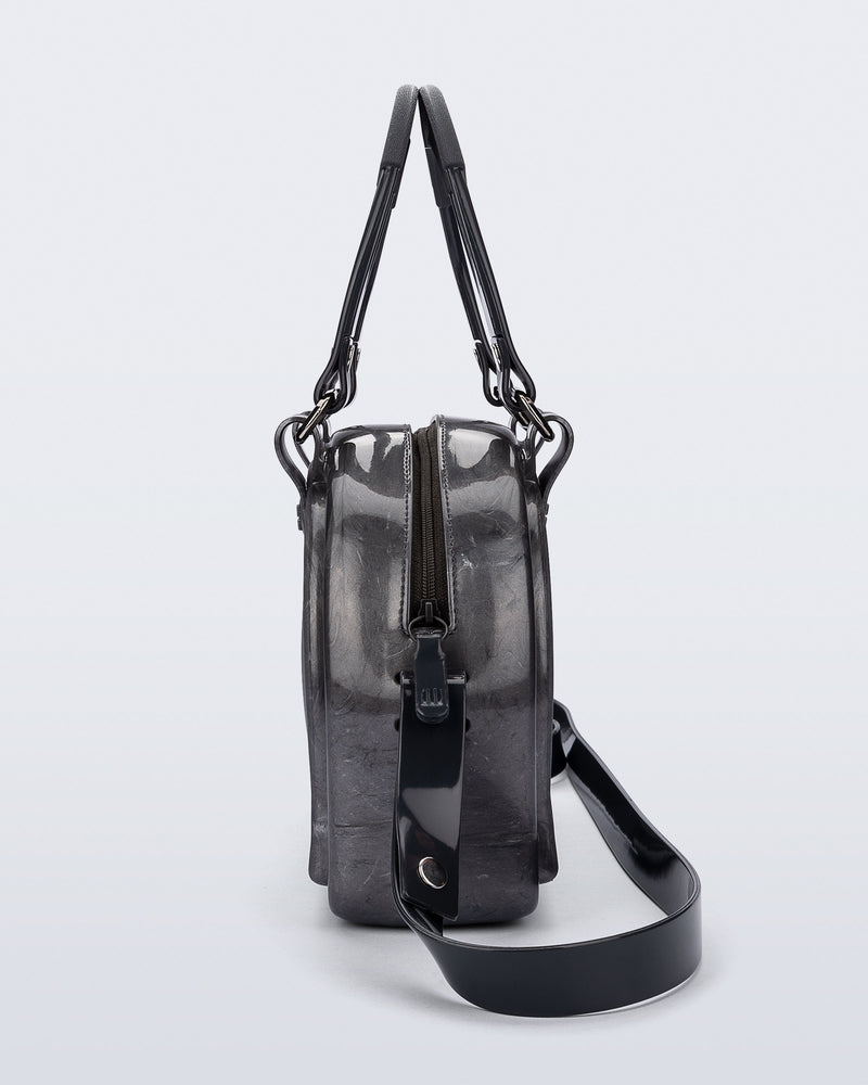 Side view of a grey Bowling bag with black handle strap and cross body strap