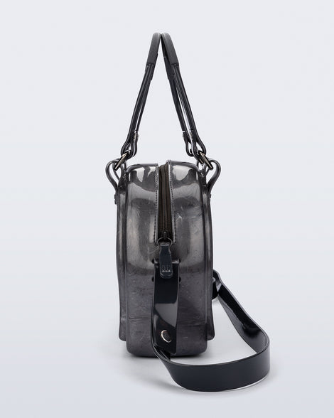 Side view of a grey Bowling bag with black handle strap and cross body strap