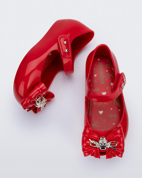 Top and side view of a pair of red Ultragirl Princess ballerina baby flats with bow on top and silver details