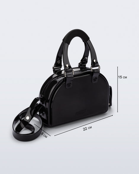 Angled view of a black Bowling bag with handle strap and cross body strap with bag dimensions of 22cm x 8cm x 15cm