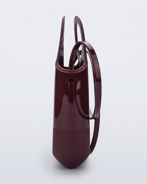 Side view of a burgundy Ultra Bag with handle and strap
