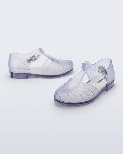 Side and angled view of a pair of clear Aranha 79 kids flats with buckle