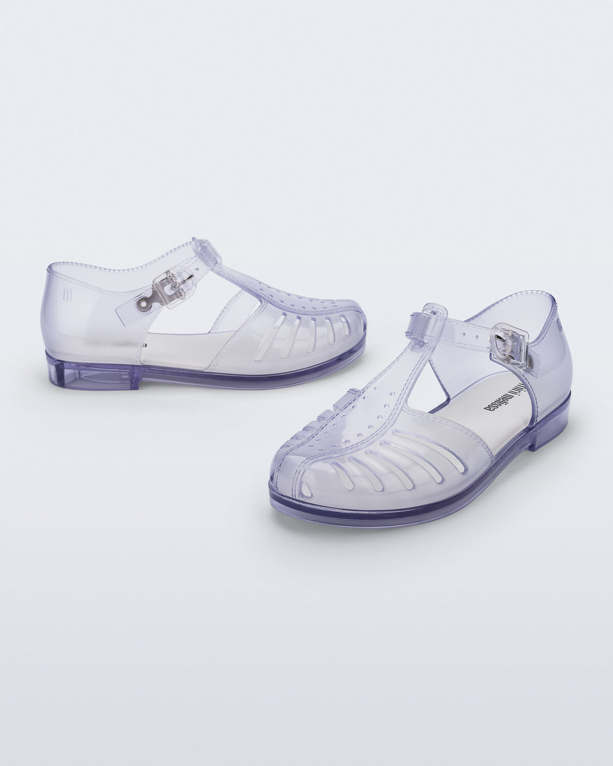 Side and angled view of a pair of clear Aranha 79 kids flats with buckle