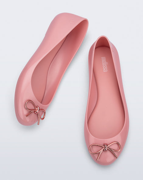 Top and angled view of a pair of pink Sweet Love Chrome flats with metallic pink bow