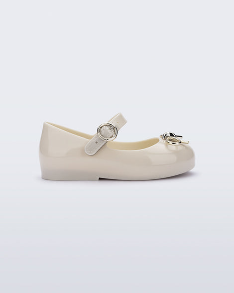Side view of a beige Sweet Love Chrome baby flat with metallic gold bow and buckle