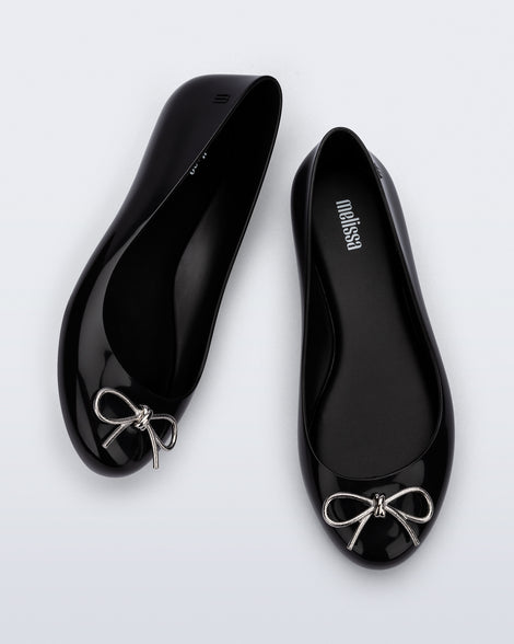 Top and angled view of a pair of black Sweet Love Chrome flats with silver bow