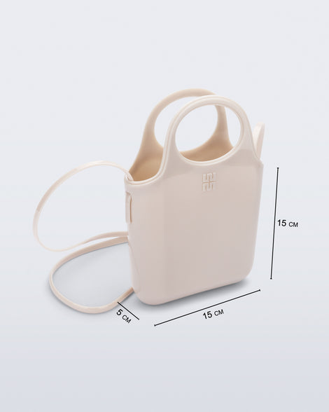 Angled view of a beige Ultra Bag with handle and strap with bag dimensions of 15cm x 5cm x 15cm