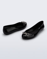 Back and angled view of a pair of black Sweet Love Chrome flats with silver bow