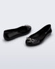 Back and angled view of a pair of black Sweet Love Chrome flats with silver bow