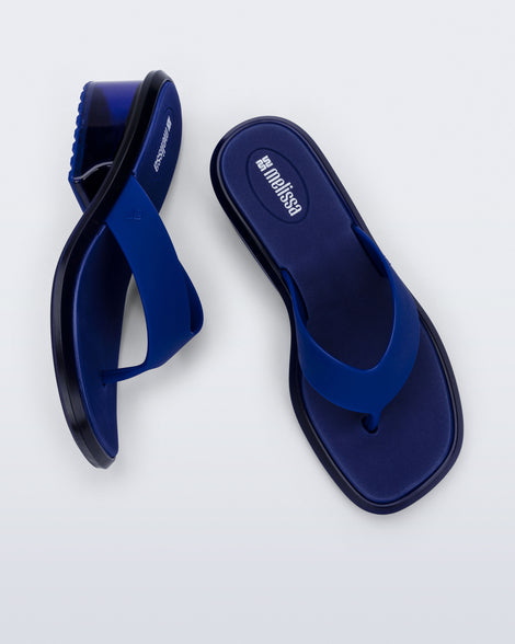 Top and side view of a pair of blue Margot flip flops with clear blue low heel 
