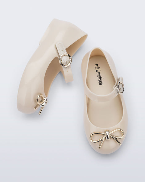 Top and side view of a pair of beige Sweet Love Chrome baby flats with metallic gold bow and buckle