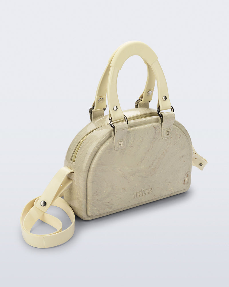 Angled view of a beige Bowling bag with handle straps and cross body strap