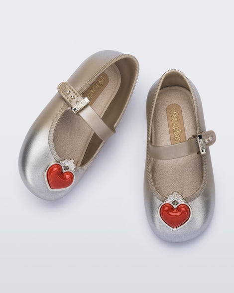 Top view of a pair of gold/silver Soft Ballerina Princess baby flats with a red heart on top