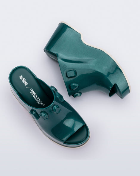Top and side view of a pair of metallic green Patty Stones + Undercover platform open toe mules with beige sole and stone embellishments on upper.