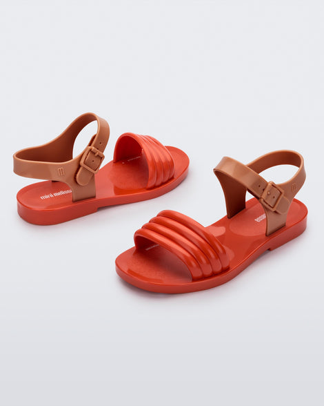 Angled view of a pair of red Mar Wave kids sandals with brown strap.