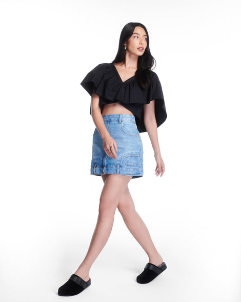Model in a jean skirt and black top wearing a pair of black Cozy Clog Velvet slides
