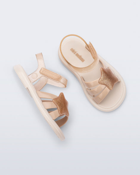 Side and top view of a pair of beige Hip Sky baby sandals with a glitter beige star on top