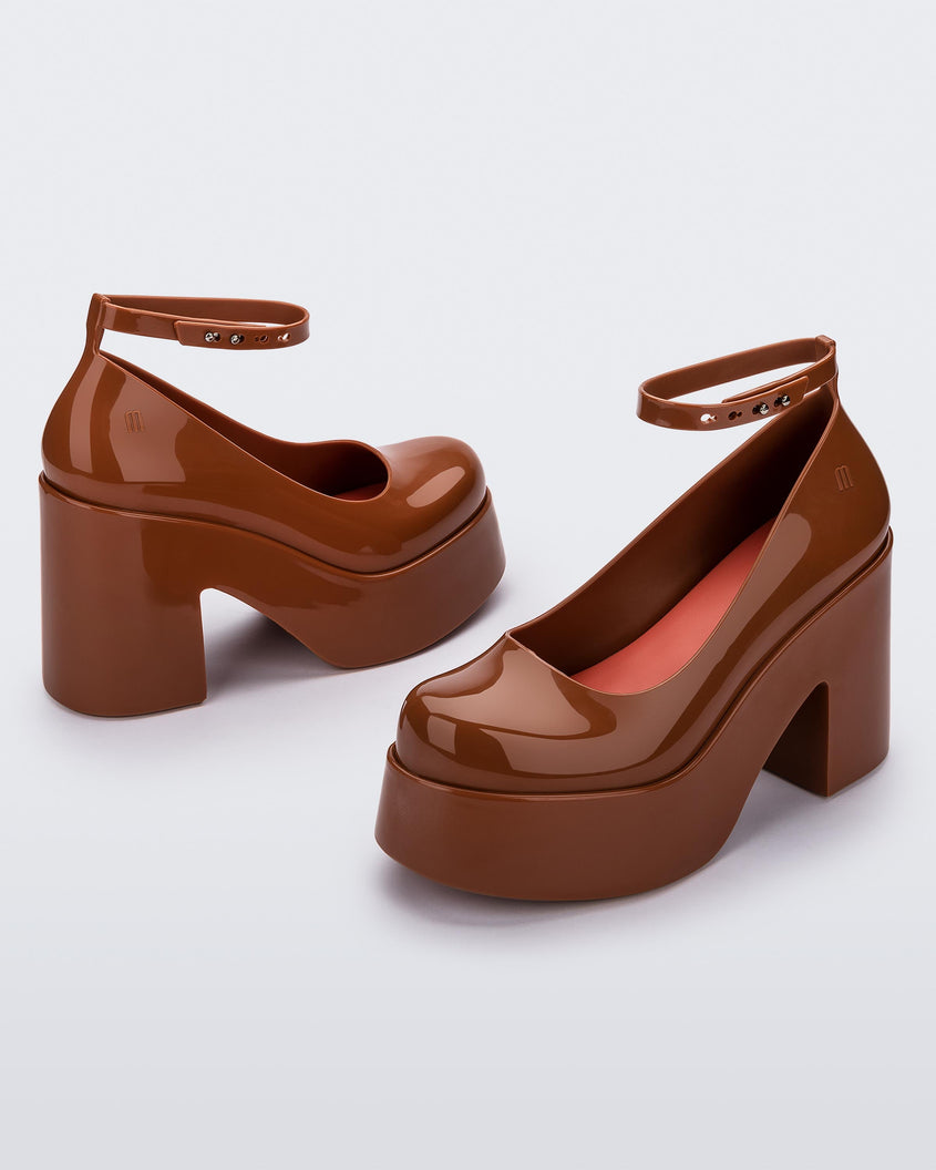 Angled view of a pair of brown Melissa Doll Heel platforms with ankle strap and red insole.