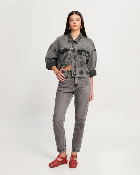 Model in black jean pants and jacket wearing a pair of red Possession Pescura + Scholl fisherman sandals