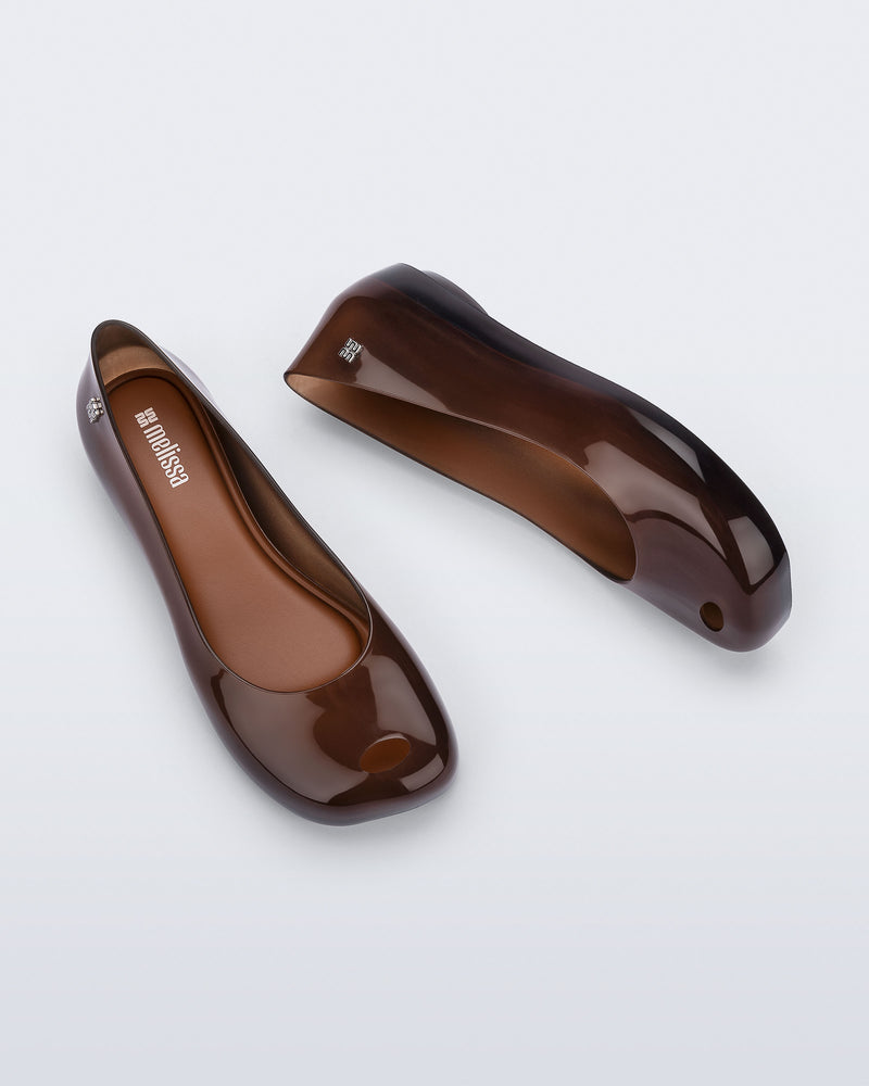Top and side view of a pair of clear brown Ultragirl Futura flats