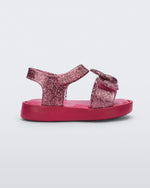 Side view of a glitter pink Mini Melissa Jump sandal with a Mickey Mouse logo detail on the front strap and an ankle strap