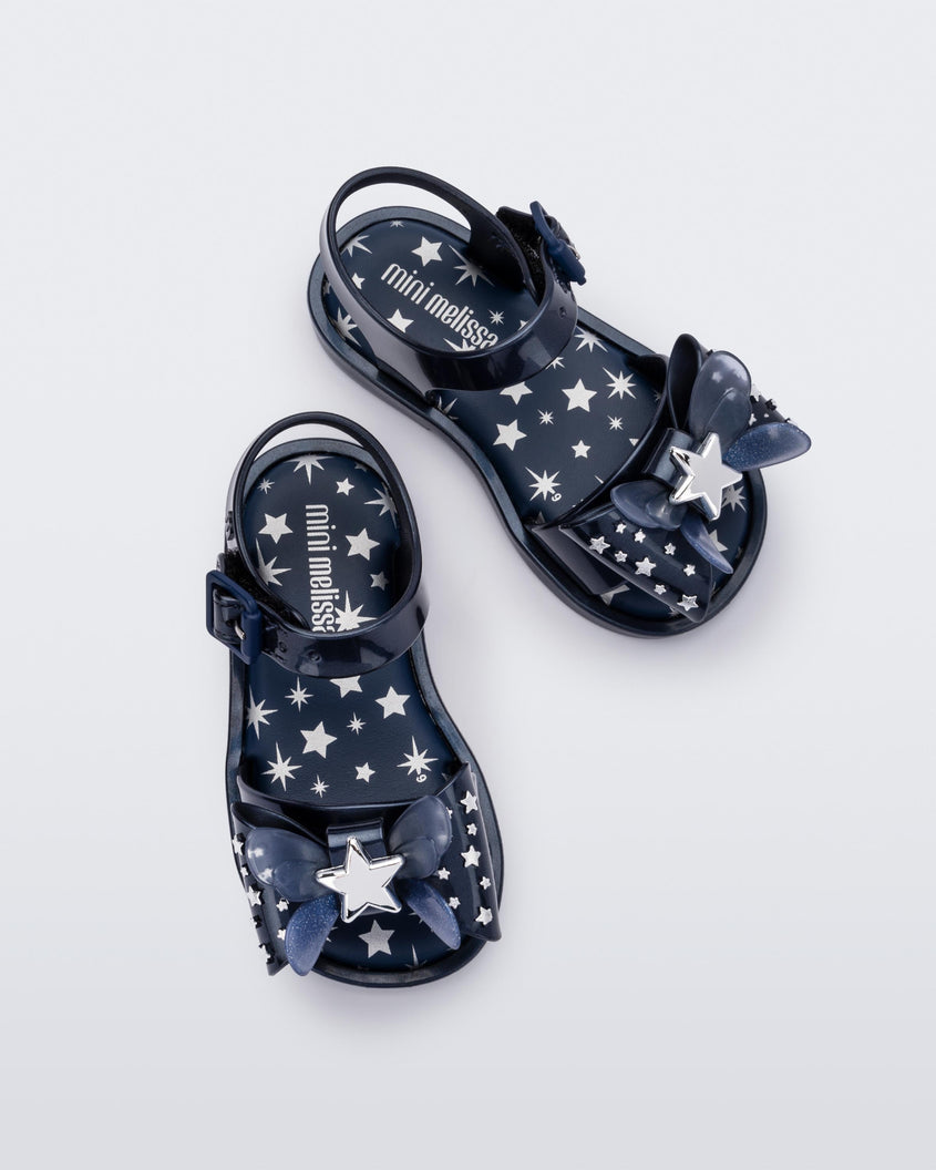 Overhead view of a pair of Mini Melissa Mar Sandals with star print for baby in blue with butterfly bow applique and velcro closure on ankle strap.