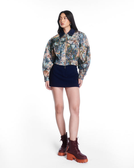 Model in a black skirt and multicolored jacker wearing a pair of burgundy Track Boot with small heel and burgundy laces and orange sole