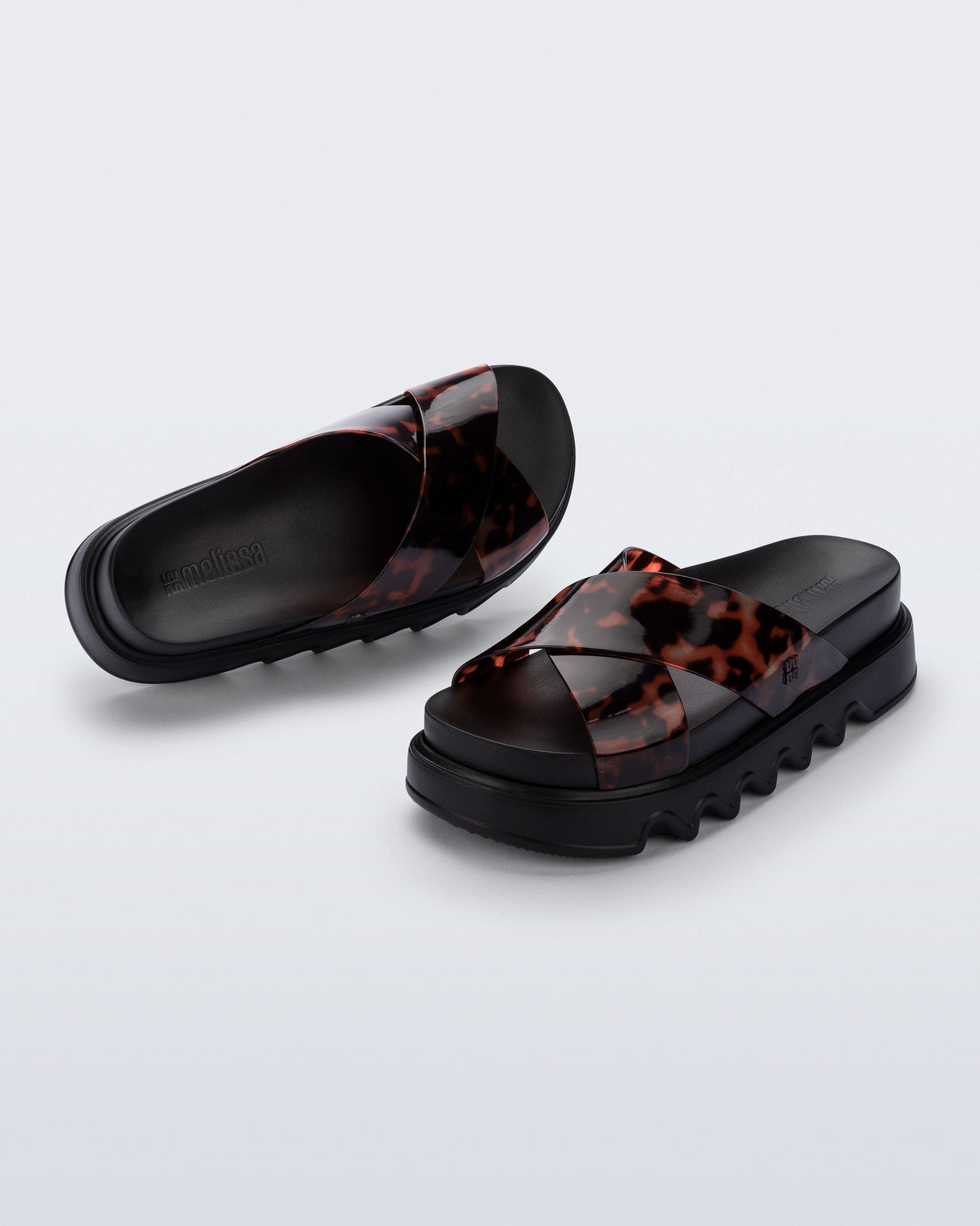 Top and angled view of a pair of black/tortoise Cozy Cross platform sandals with crisscross top straps
