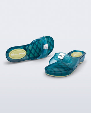 Top and angled view of a pair of clear blue Pescura Heel + Scholl slides with top buckle