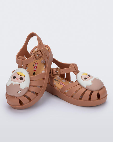 Angled view of a pair of beige Possession + Pop Mart Pucky fisherman baby sandals