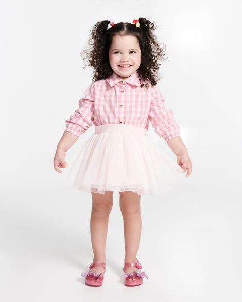 Child model in a pink shirt and white tutu skirt wearing a pair of pink glitter Ultragirl Butterfly baby flats with pink butterflies on top